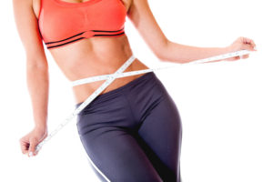 Fit woman measuring  her waist - isolated over a white background